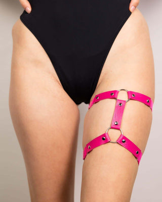 Pink leather adjustable leg garter worn with a black swimsuit, perfect for rave outfits and edgy festival styles.