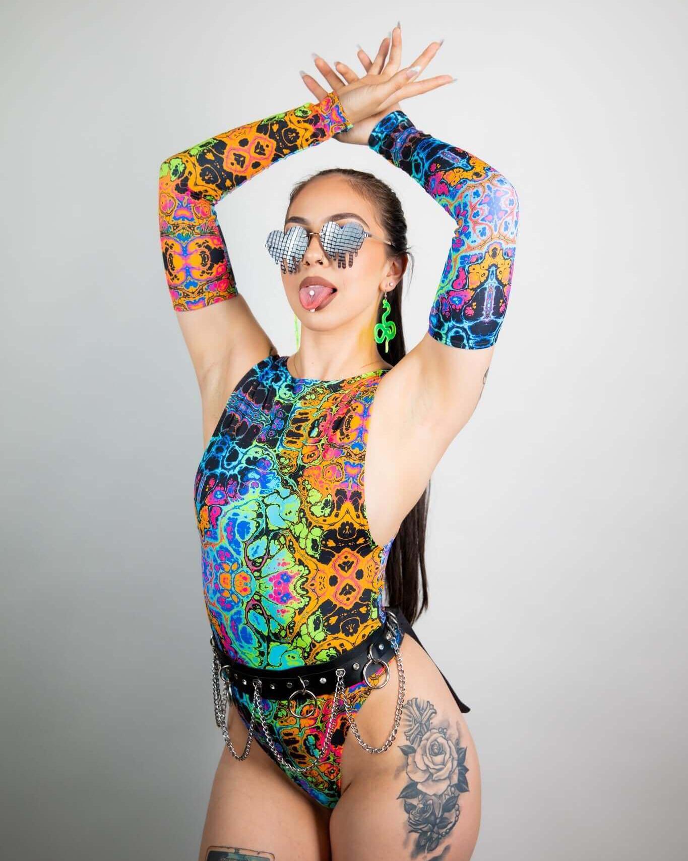 Model showcasing psychedelic rainbow arm sleeves paired with colorful bodysuit for festival wear. Perfect for rave outfits.