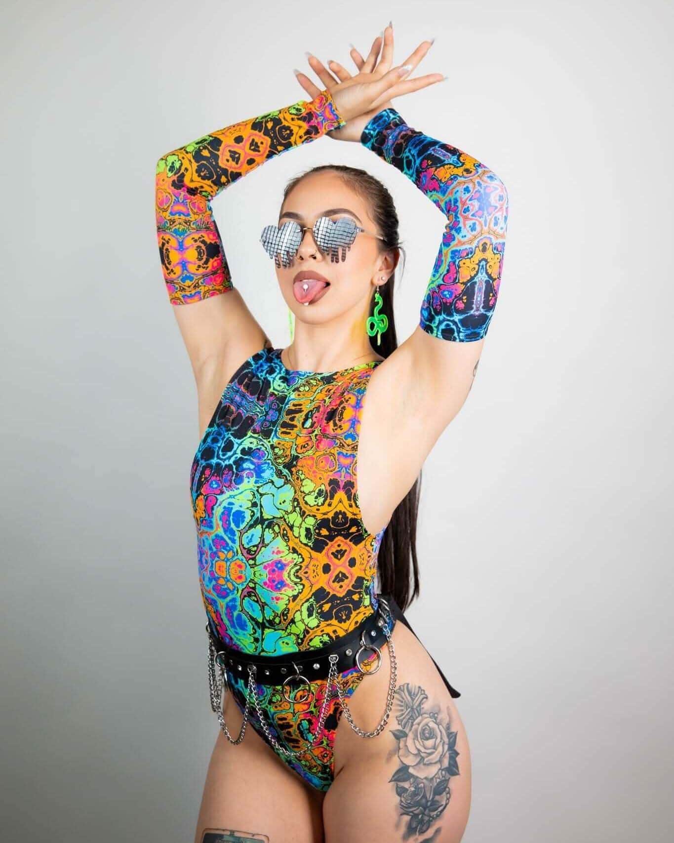 Model showcasing psychedelic rainbow arm sleeves paired with colorful bodysuit for festival wear. Perfect for rave outfits.