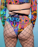 High-waisted Brazilian bottoms with psychedelic rainbow design, paired with fishnet stockings for rave outfits.