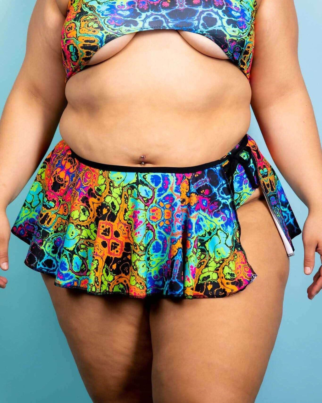 Vibrant Lucidity Swirl Skirt in rainbow colors, styled with a coordinating top, perfect for rave outfits and summer fun.