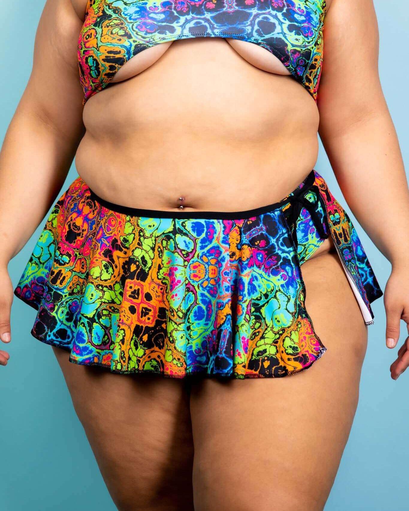 Vibrant Lucidity Swirl Skirt in rainbow colors, styled with a coordinating top, perfect for rave outfits and summer fun.