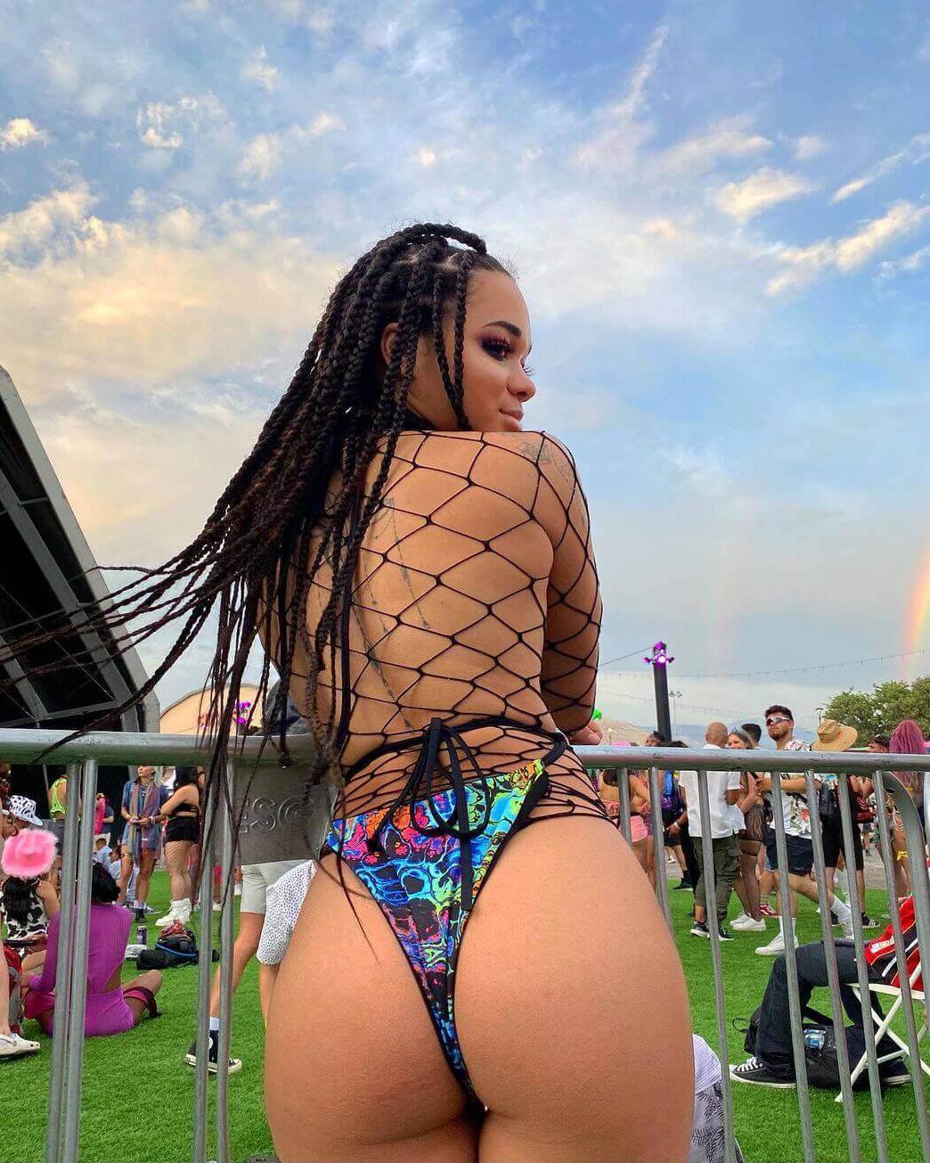 Woman wearing a colorful rave outfit with fishnet detail at a festival, showcasing a psychedelic design and vibrant atmosphere.