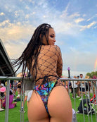 Woman wearing a colorful rave outfit with fishnet detail at a festival, showcasing a psychedelic design and vibrant atmosphere.