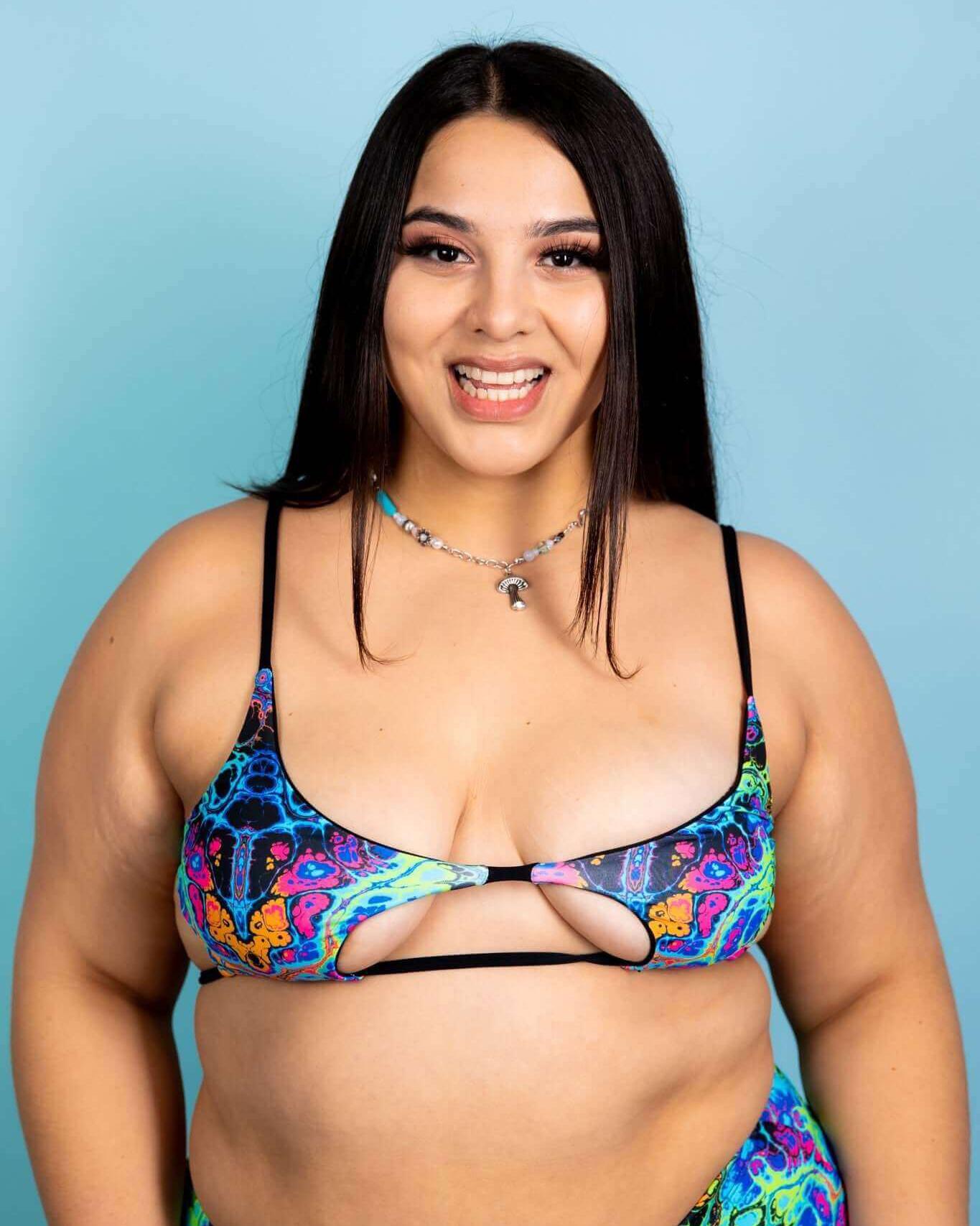 Vibrant psychedelic rainbow bikini top on model, perfect for rave outfits and festival vibes.