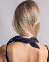 Matte black bandana tied around a woman's neck, showcasing a chic look for rave outfits and festivals.