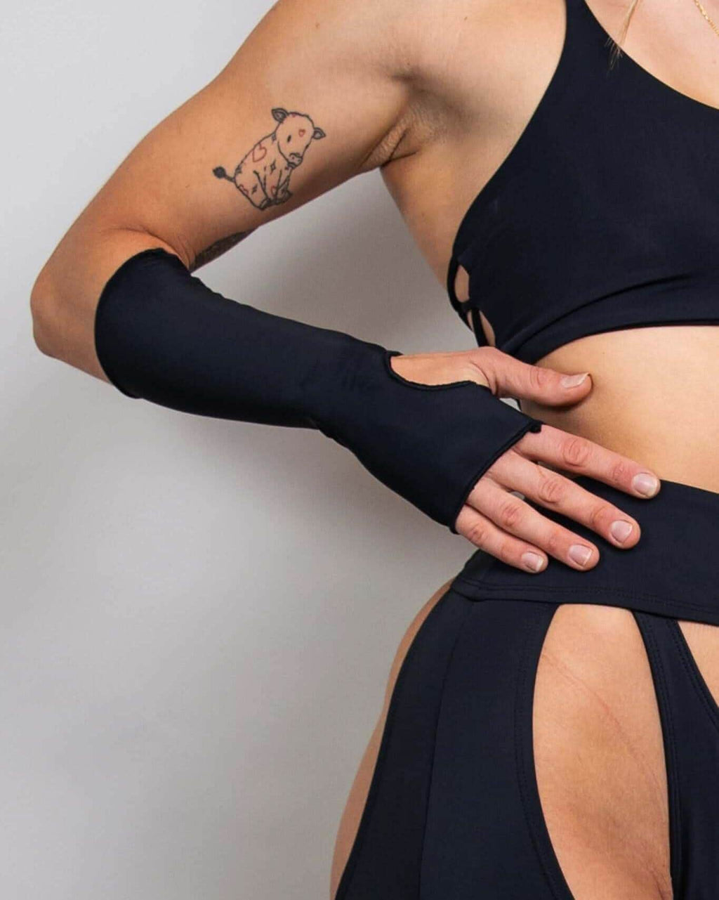 Matte black gloves worn with a stylish black outfit, featuring a thumb hole and a comfortable forearm fit, perfect for rave outfits.