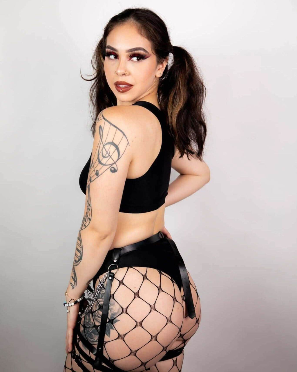 Model showcasing a matte black high waisted thong paired with fishnet stockings, perfect for rave outfits.