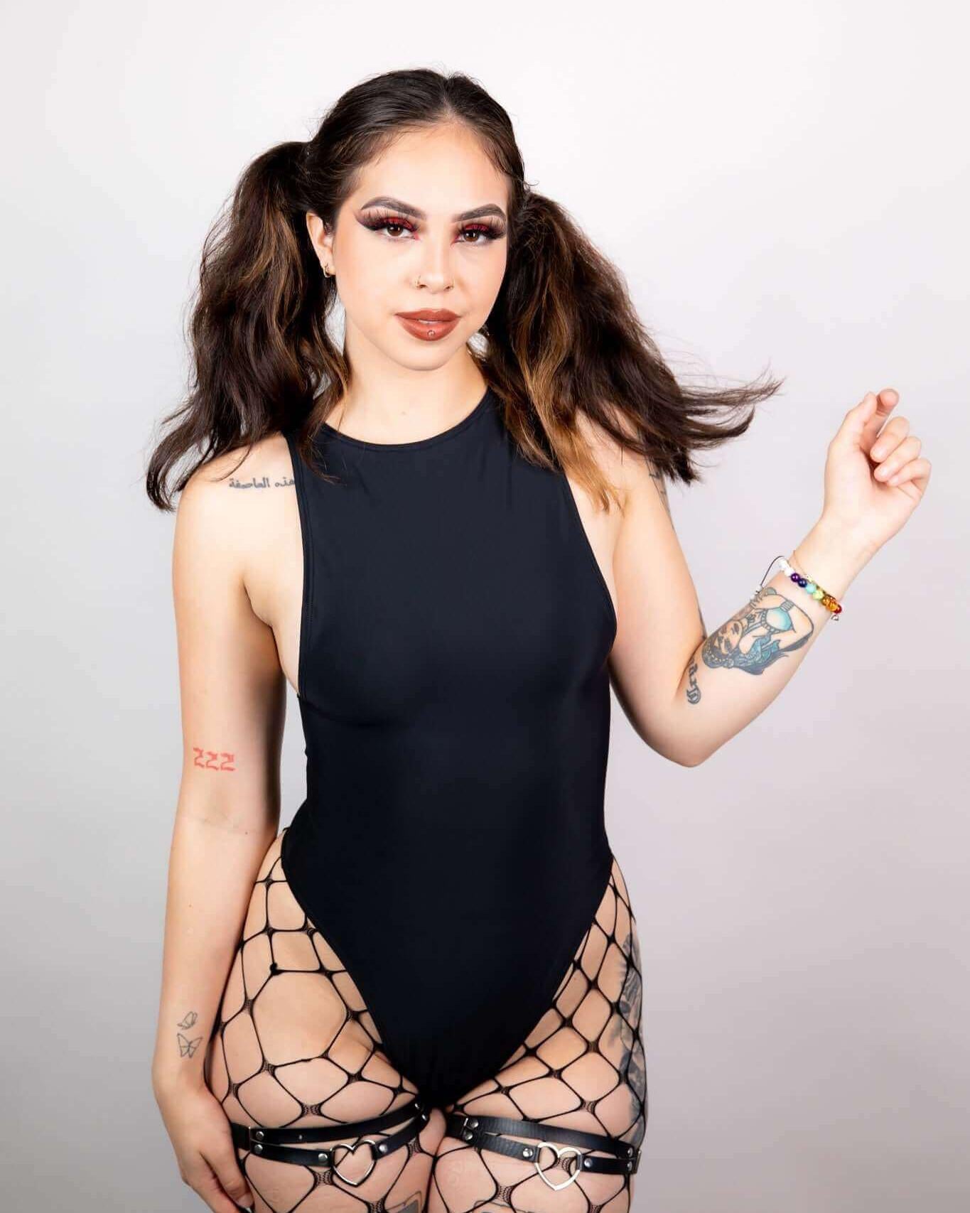 Woman in a matte black sideboob bodysuit paired with fishnet stockings, perfect for rave outfits and festivals.