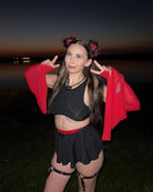 Model in a black swirl skirt with red accents posing at dusk, showcasing a stylish rave outfit.