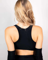 Woman wearing a back view of a matte black racerback teaser top, ideal for rave outfits and EDM events.