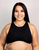 Woman wearing a matte black racerback teaser top, showcasing underboob style, perfect for rave outfits.