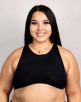 Woman wearing a matte black racerback teaser top, showcasing underboob style, perfect for rave outfits.