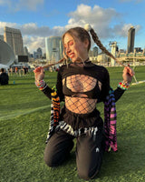 Young woman in a fishnet top and relaxed pants, showcasing playful rave outfit against a cityscape backdrop.