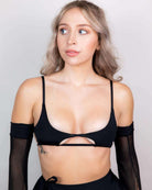 Model wearing a black matte cut-out top with tie straps, showcasing chic style perfect for rave outfits.