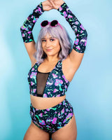 Model showcasing Mushies arm sleeves and matching rave outfit with a playful design against a blue background.