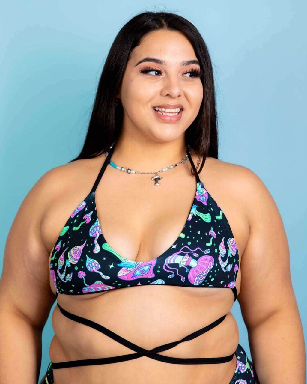 Model in Mushies Extra Mile Bralette featuring colorful prints, perfect for rave outfits, with criss-cross straps.