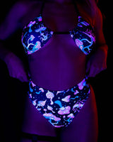 Model wearing Mushies High Waisted Thong and matching top, glowing in blacklight, perfect for rave outfits.