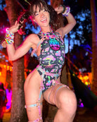Person wearing a psychedelic mushroom bodysuit, showcasing a vibrant rave outfit at an outdoor festival.