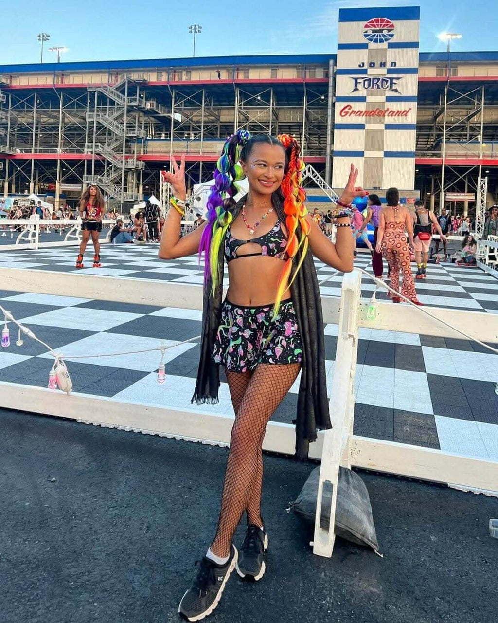 Colorful festival attendee in a rave outfit with rainbow hair, showcasing a fun and vibrant style at an outdoor event.