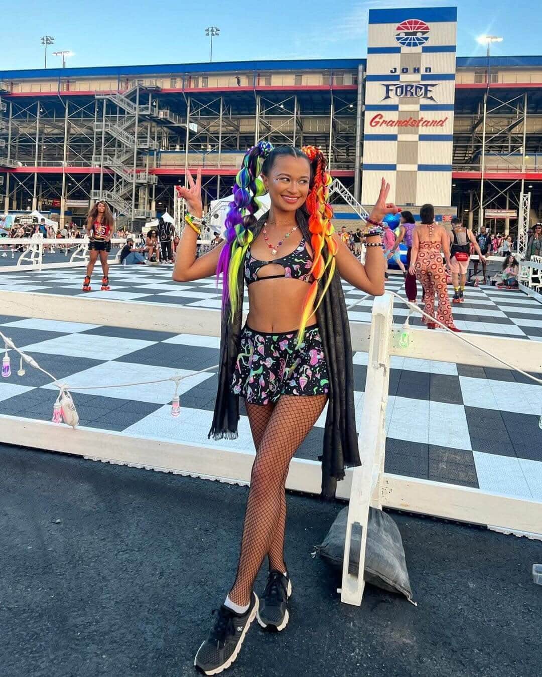 Colorful festival attendee in a rave outfit with rainbow hair, showcasing a fun and vibrant style at an outdoor event.