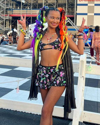 Young woman in colorful rave outfit posing with vibrant hair at a lively outdoor event. Perfect for festival vibes.