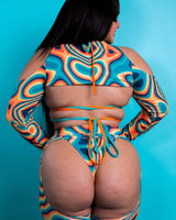Back view of a model wearing vibrant Orange Crush Spectra Sleeves and matching outfit, showcasing '70s-inspired grooves.
