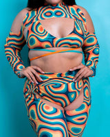 Model wearing Orange Crush Spectra Sleeves with a vibrant orange-teal pattern, showcasing trendy rave outfit style.
