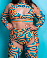 Model showcasing vibrant orange-teal cut-out rave outfit featuring futuristic design and soft stretchy fabric.