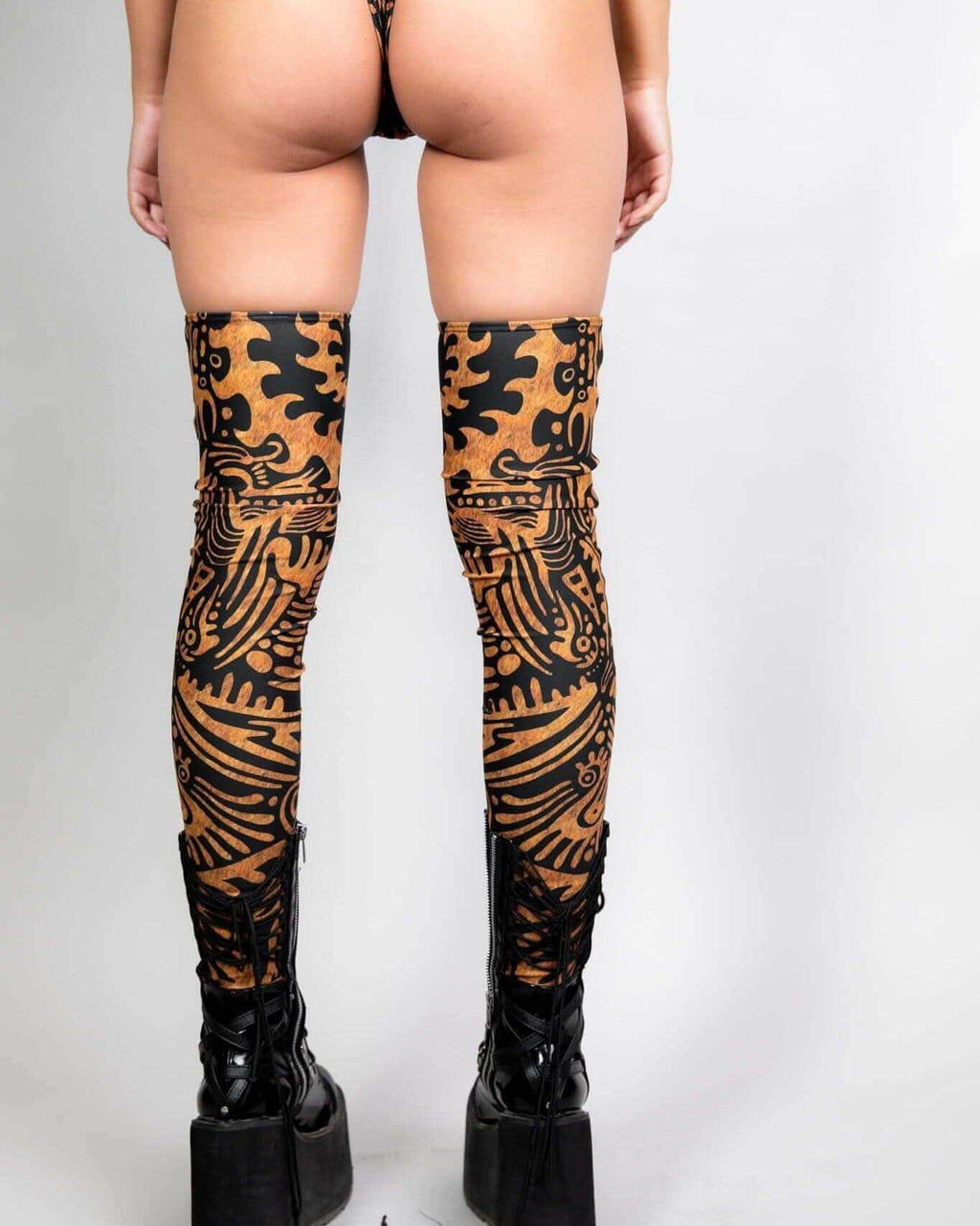 Primal Leg Sleeves in tribal pattern worn with high-heeled boots, perfect for rave outfits and bold statements.