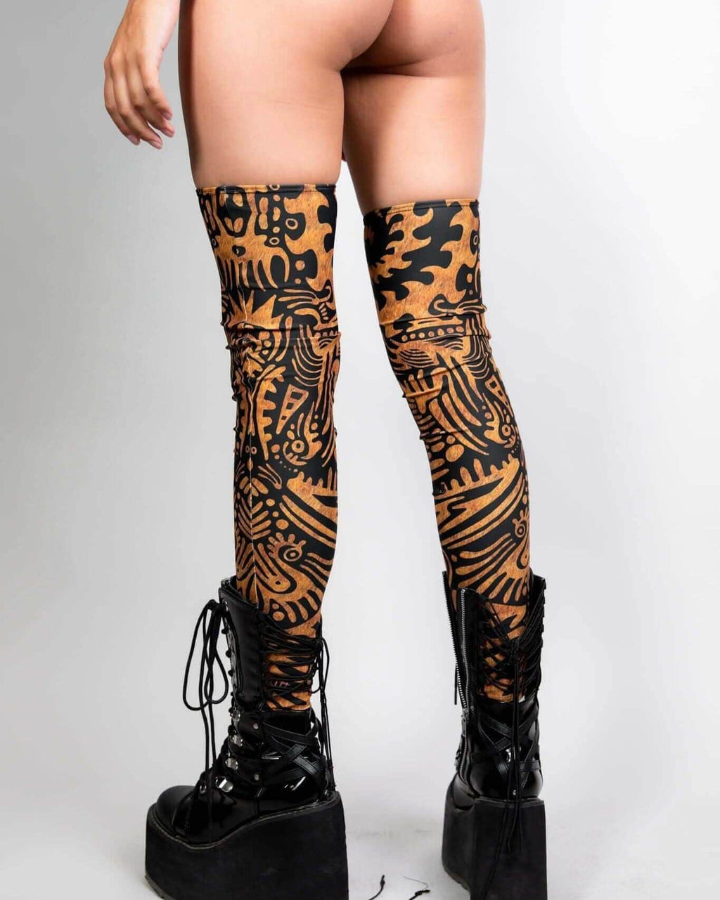 Model showcasing Primal Leg Sleeves with bold tribal print, paired with black platform boots, perfect for rave outfits.