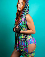 Young woman in a vibrant prismatic festival scarf and outfit, showcasing rave style against a teal background.