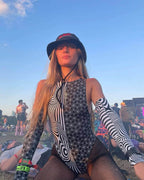 Model wearing Duality rave arm sleeves with geometric black white patterns at outdoor festival setting