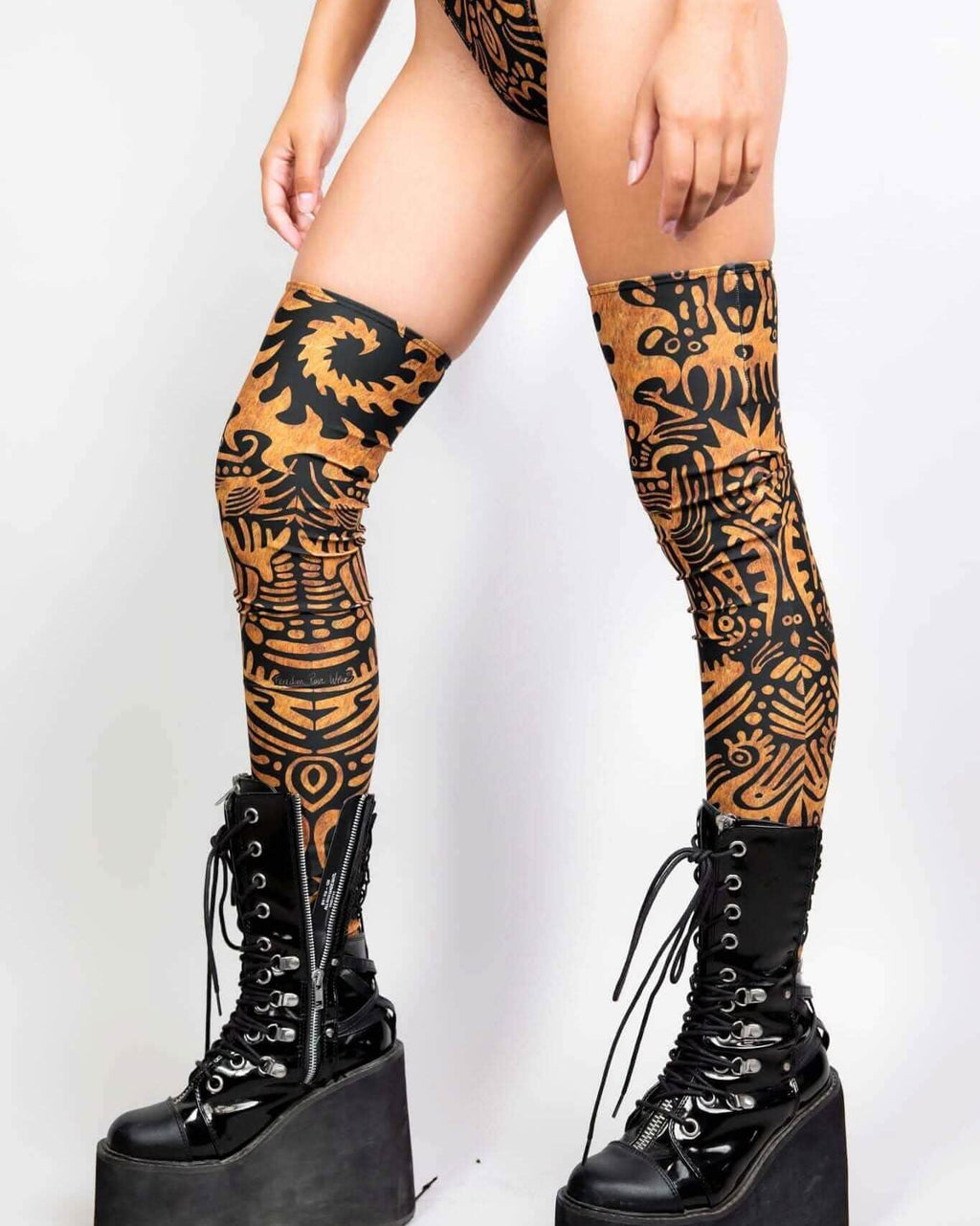 Primal rave arm sleeves in copper and black tribal print worn with platform boots festival outfit front view