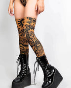 Primal rave arm sleeves in copper with black tribal patterns worn as thigh-high leg sleeves with platform boots