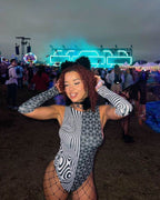 Woman wearing Duality rave bodysuit with geometric black white pattern at festival with stage lights
