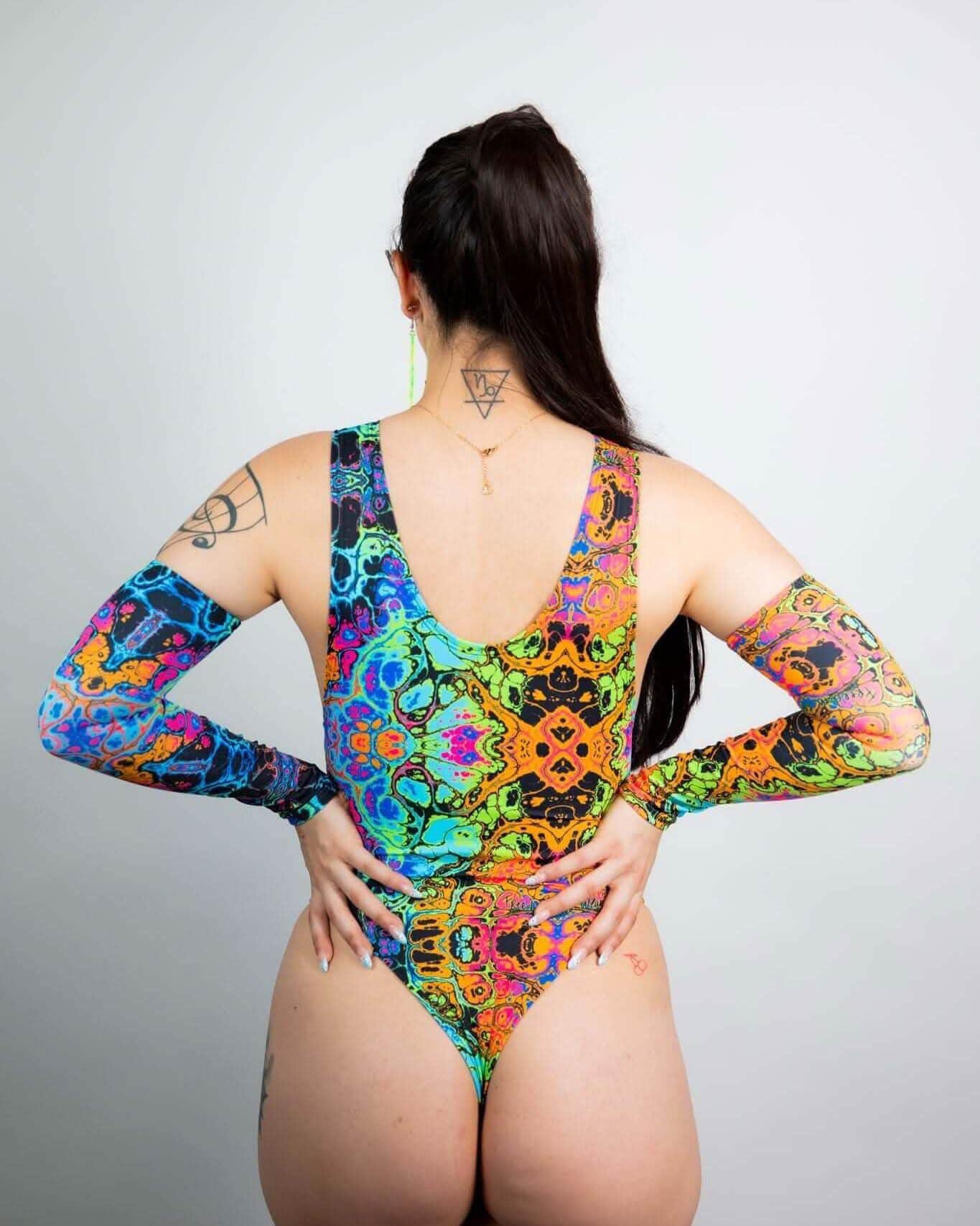 Back view of model wearing Lucidity psychedelic rainbow rave bodysuit with long sleeves and sideboob cutouts
