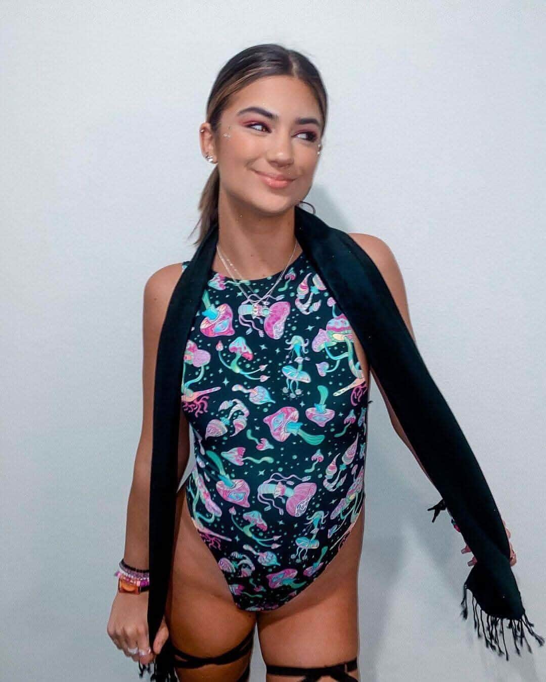 Woman modeling Mushies sideboob rave bodysuit with psychedelic mushroom print in festival outfit pose