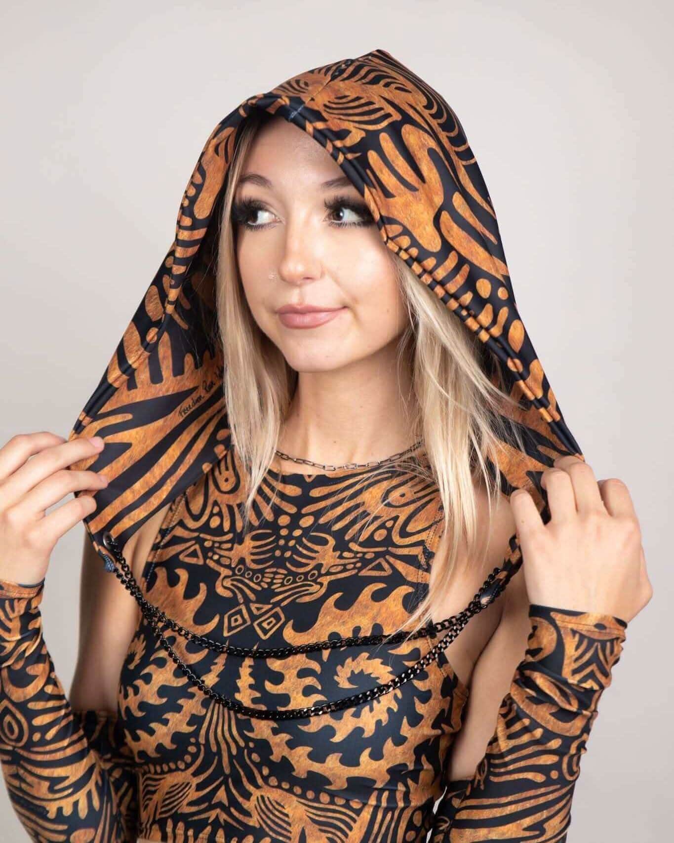 Woman modeling Primal Assassin rave bodysuit hood in orange black tribal pattern for festival outfit