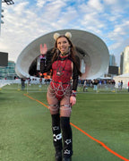 Model wearing Red Void rave bodysuit with spiral pattern at outdoor festival venue lifestyle shot