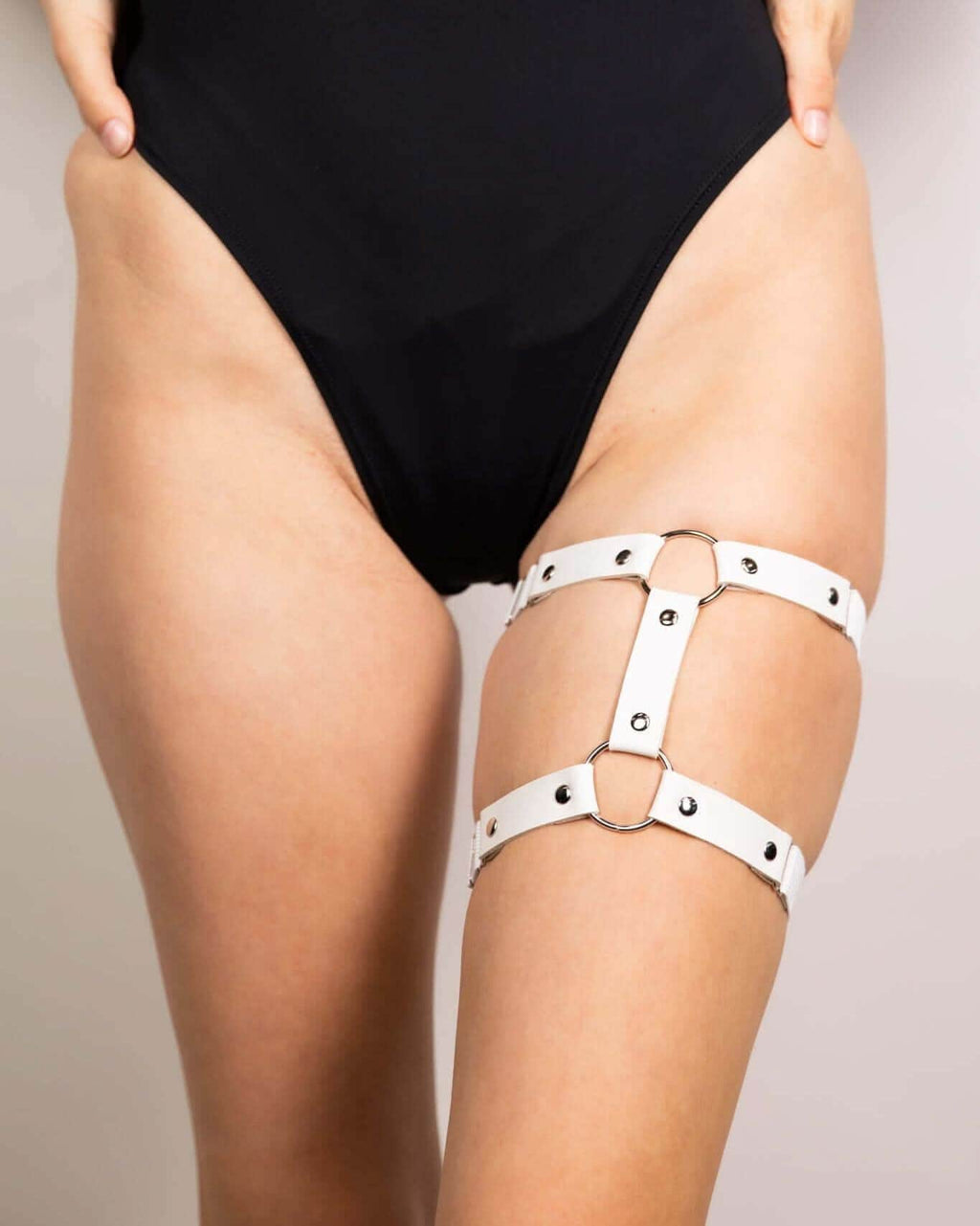 White leather adjustable leg garter worn with black rave bodysuit festival outfit detail shot