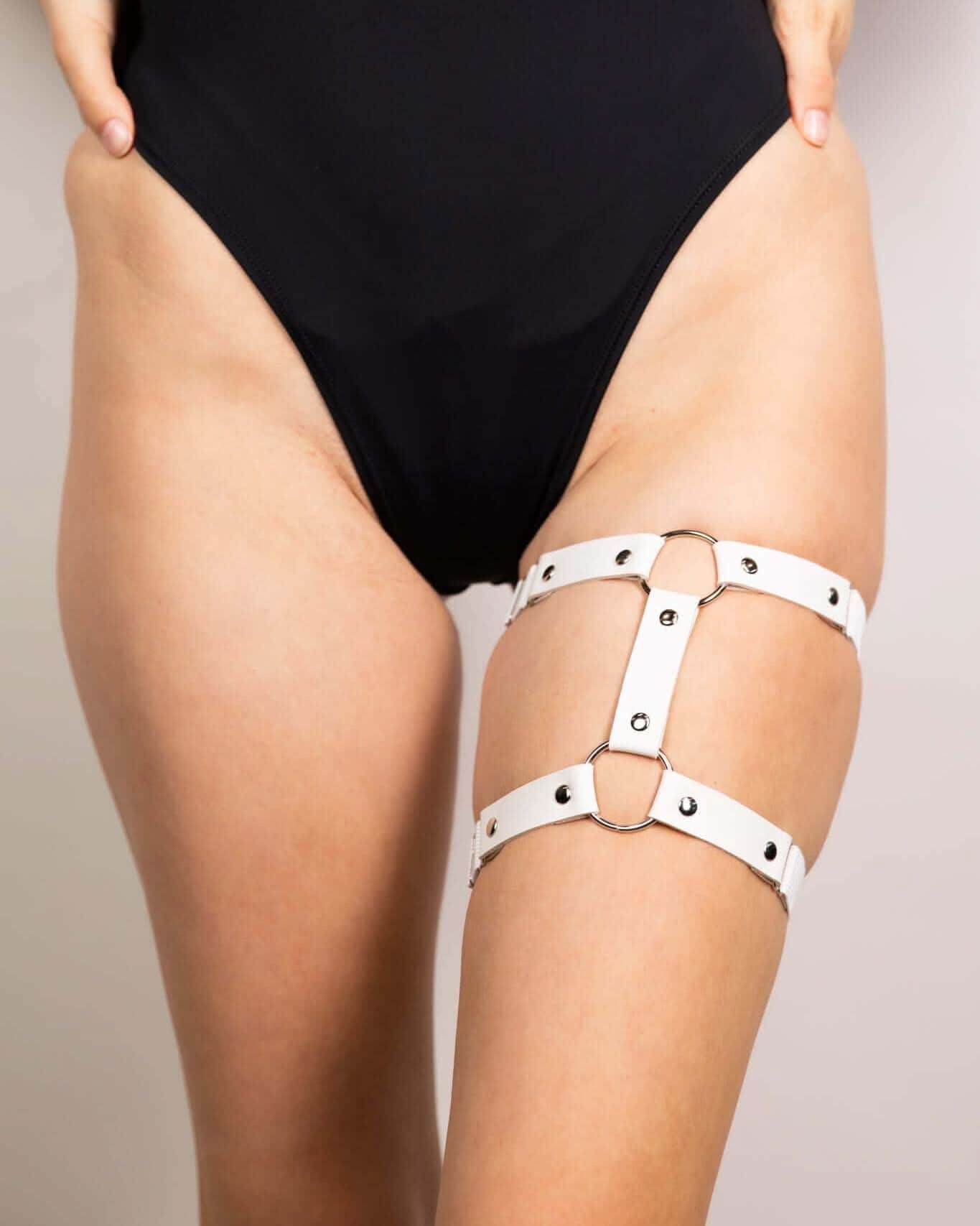 White leather adjustable leg garter worn with black rave bodysuit festival outfit detail shot