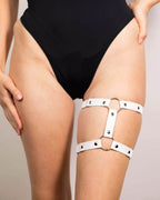 White leather adjustable leg garter with metal rings styled with black rave bodysuit festival outfit front view