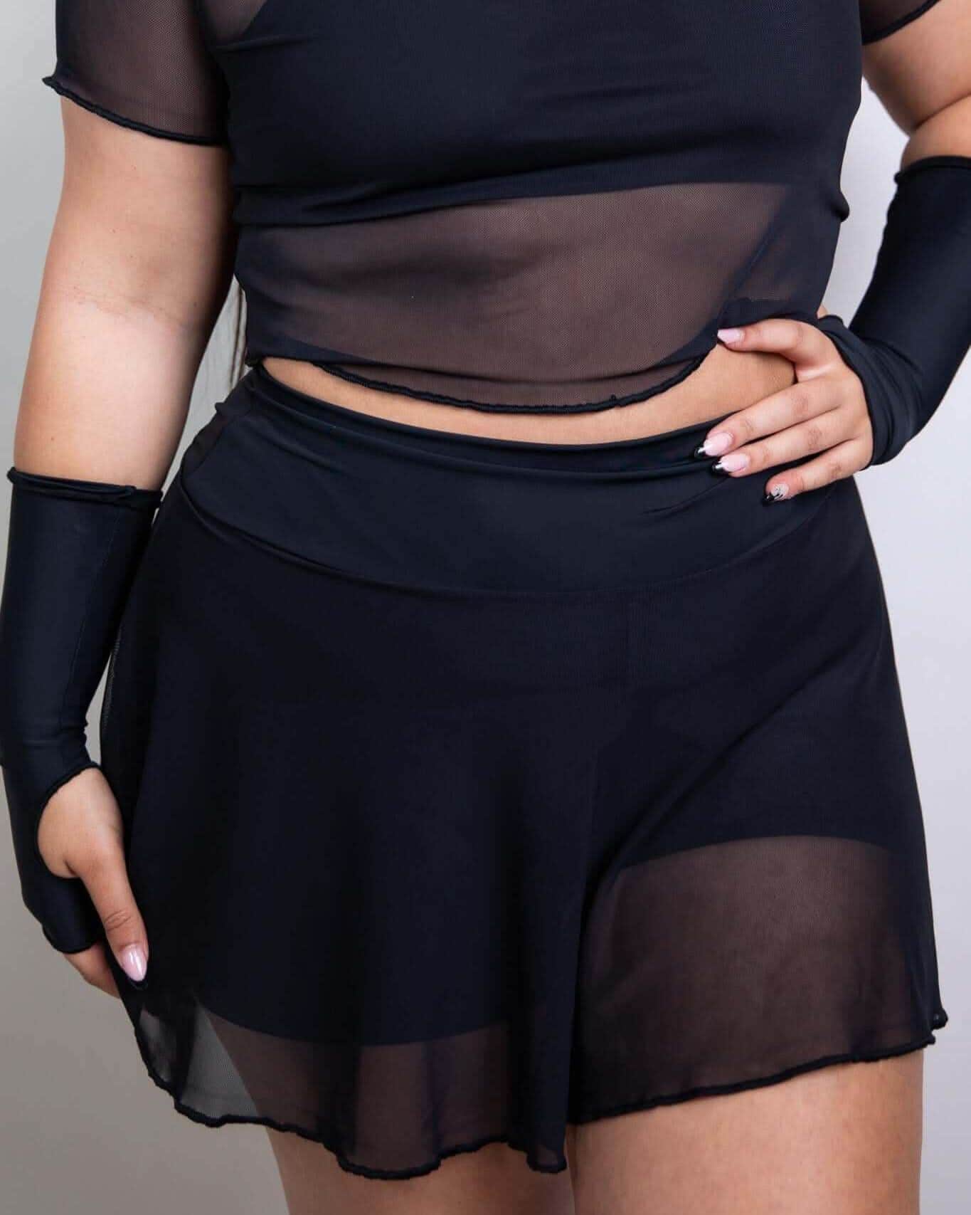 Black mesh rave pants skort front view on model, festival outfit with sheer overlay and shorts underneath