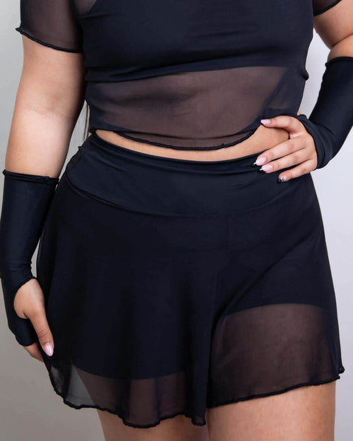Black mesh rave pants skort front view on model, festival outfit with sheer overlay and shorts underneath
