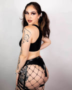 Model wearing matte black high waisted rave pants with fishnet stockings from back view