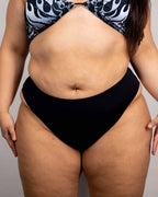 Matte black high waisted rave pants bottoms styled with patterned top, front view festival outfit