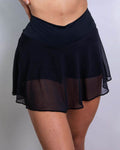 Women's matte black mesh skort rave pants with flowing overlay and built-in shorts, front view