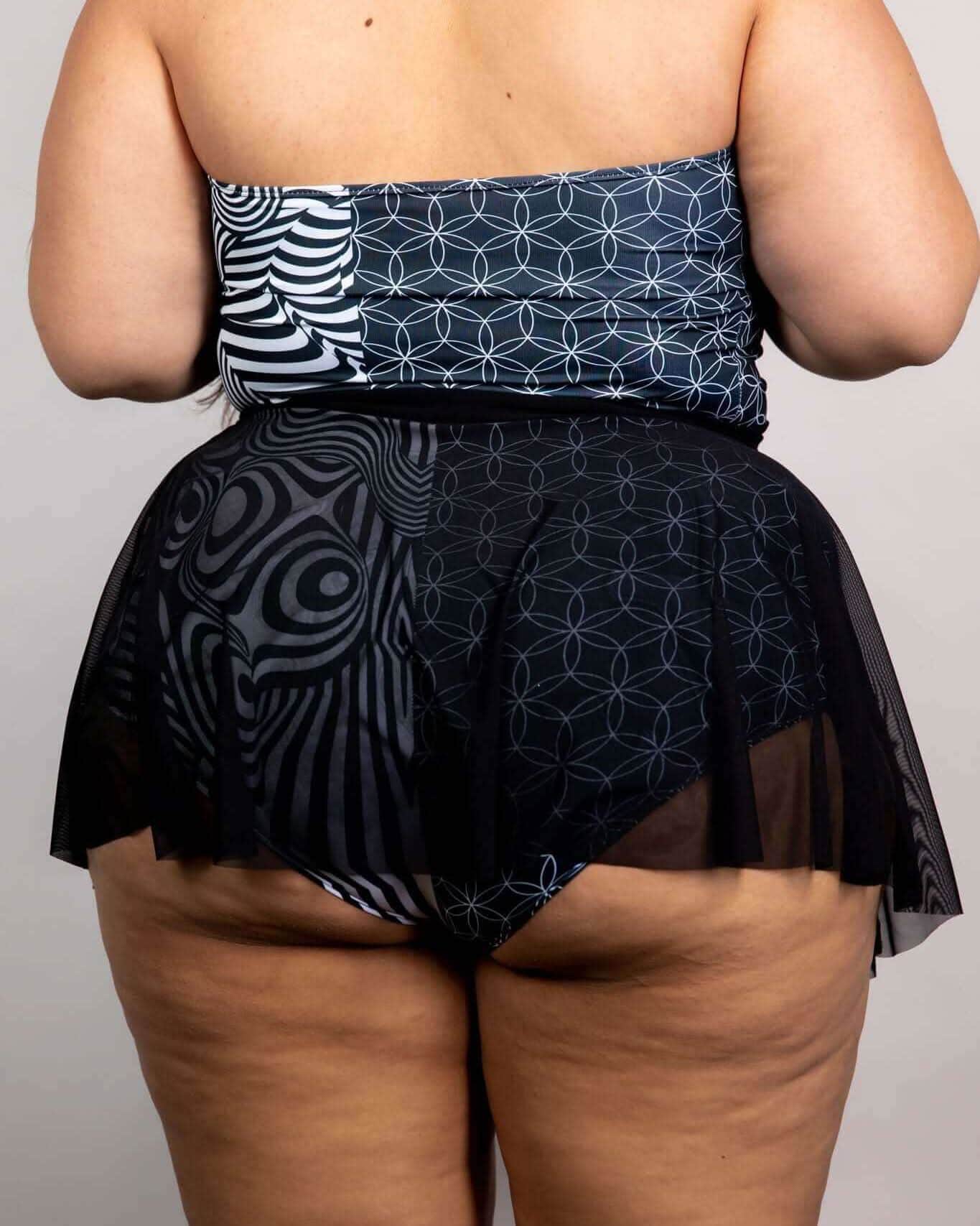 Back view of black mesh rave skirt with geometric patterns on plus-size model at festival