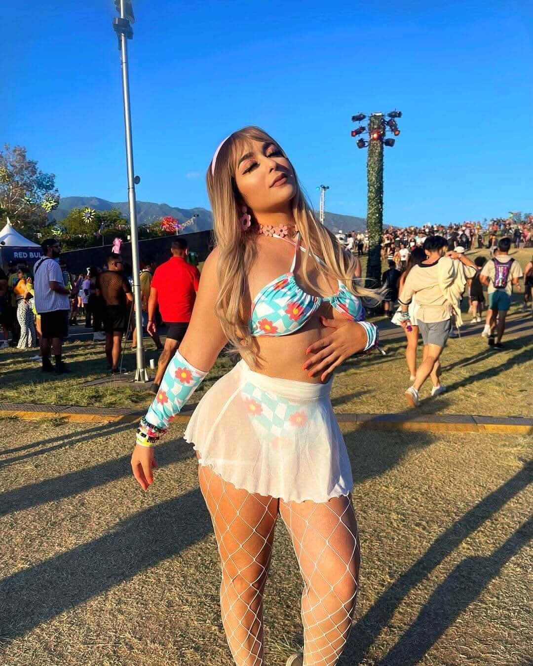 White mesh rave skirt styled at music festival with fishnet stockings and floral crop top